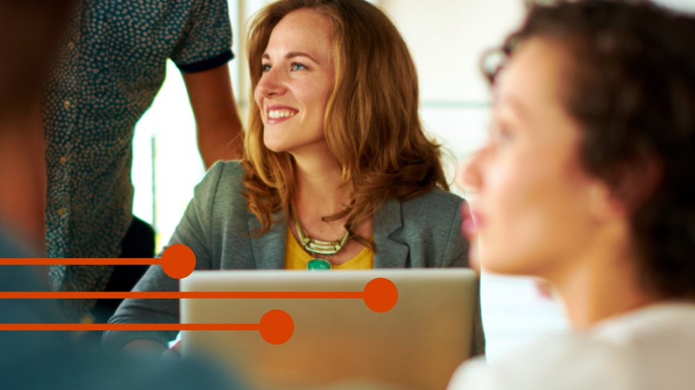 Professionals working together around a laptop in a modern office setting, representing collaborative legal research and digital workflows.